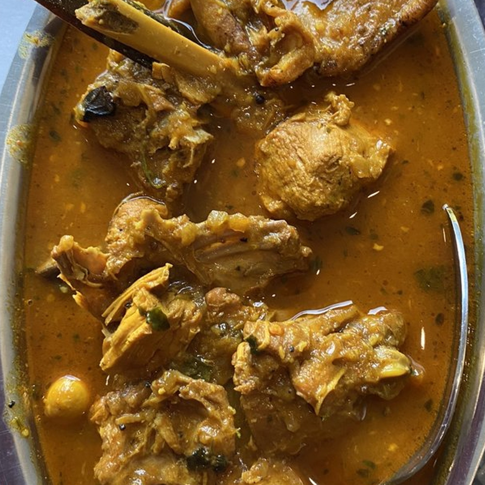 Close-up of Nepalese goat curry, featuring tender meat pieces in a rich, orange-brown sauce.