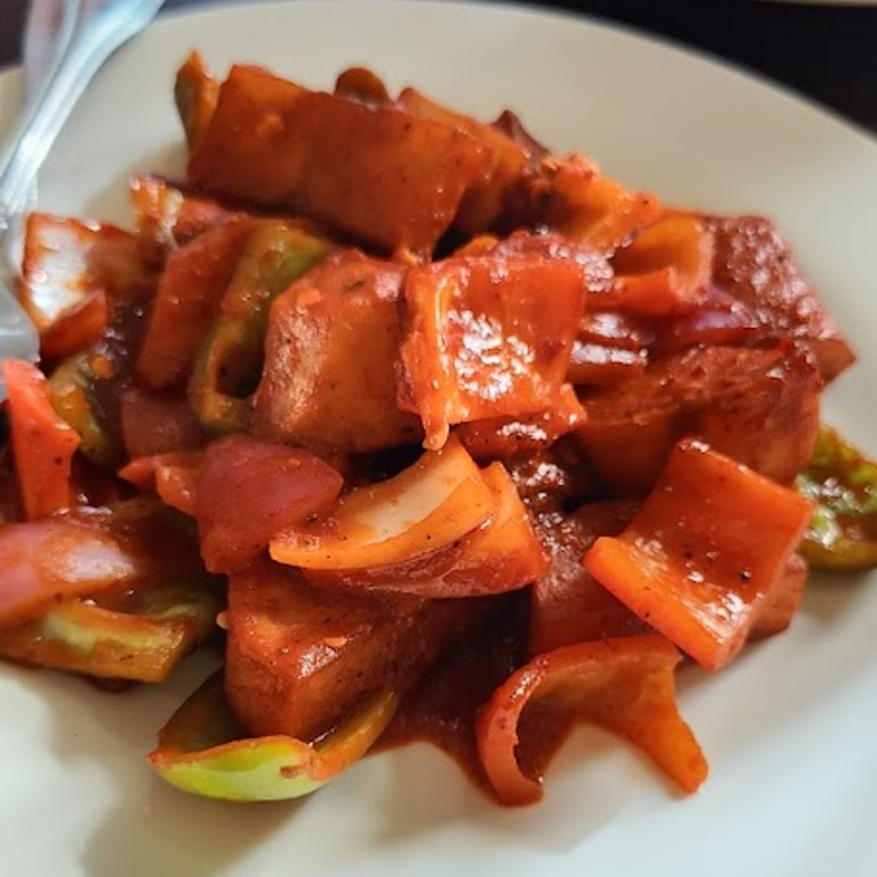 Close-up of Nepalese chili paneer with red and green bell peppers in a rich sauce.