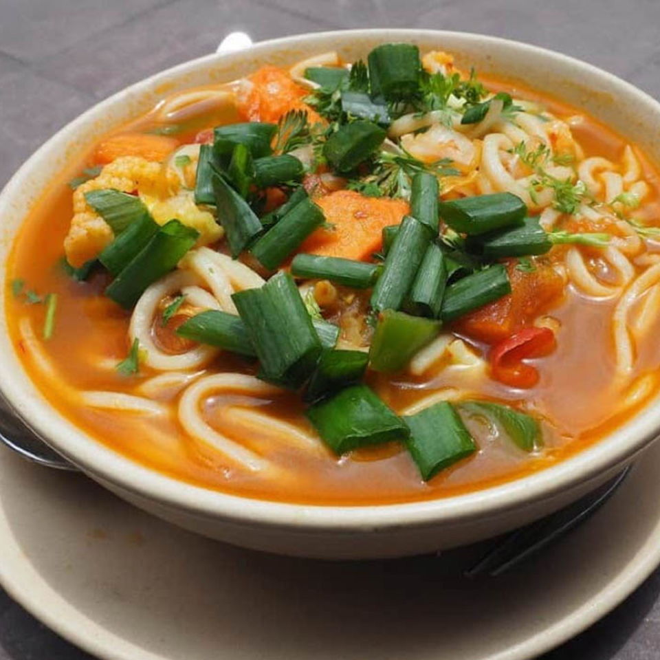 A bowl of Nepalese thukpa noodle soup with vegetables and green onions.